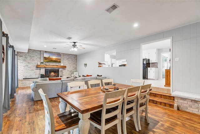 dining room featuring a fireplace, ceiling fan, and light hardwood / wood-style flooring