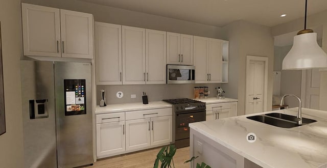 kitchen with light stone countertops, hanging light fixtures, white cabinets, appliances with stainless steel finishes, and sink