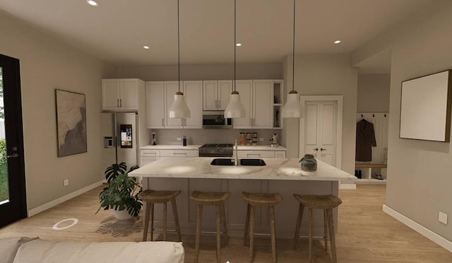 kitchen featuring appliances with stainless steel finishes, pendant lighting, an island with sink, and light stone counters