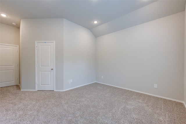 carpeted empty room with vaulted ceiling