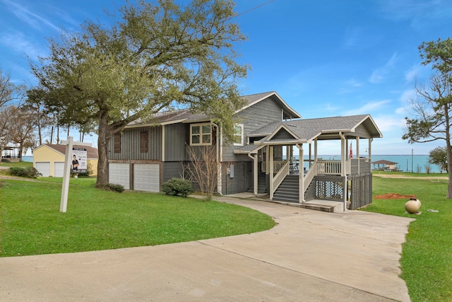 view of front facade featuring a garage, a front yard, a water view, and a porch