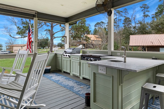 wooden terrace with grilling area, an outdoor kitchen, and a wet bar