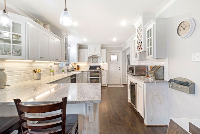 kitchen with appliances with stainless steel finishes, kitchen peninsula, a kitchen bar, and decorative light fixtures