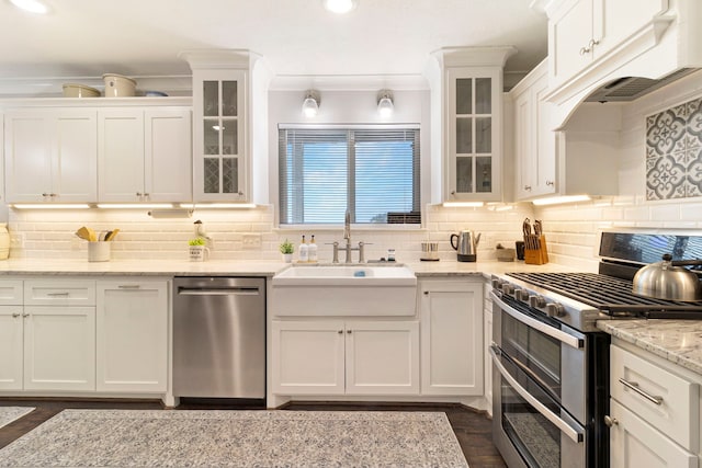 kitchen featuring sink, white cabinetry, light stone counters, stainless steel appliances, and backsplash