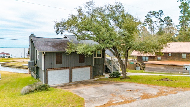 view of front facade featuring a front yard, a deck, a garage, and central air condition unit