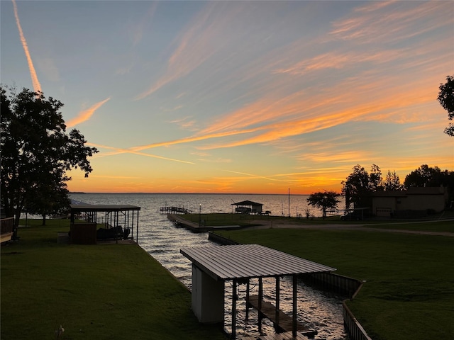 view of dock with a yard and a water view