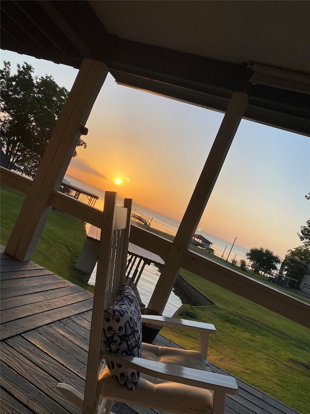 deck at dusk with a water view and a yard