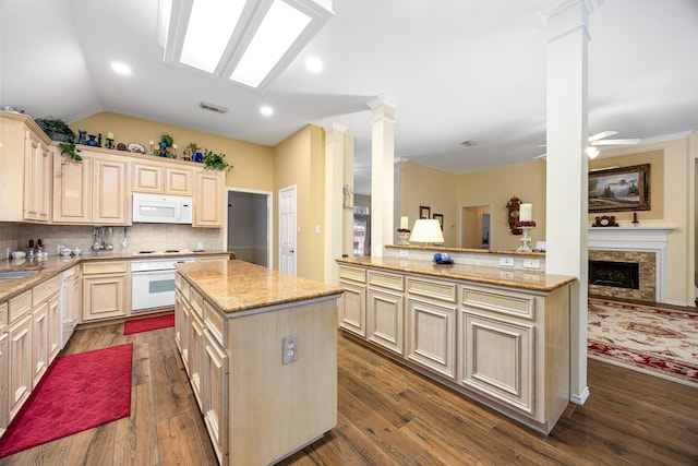 kitchen with white appliances, kitchen peninsula, vaulted ceiling, a kitchen island, and backsplash