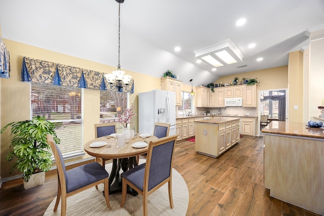 dining area with hardwood / wood-style floors, an inviting chandelier, and vaulted ceiling