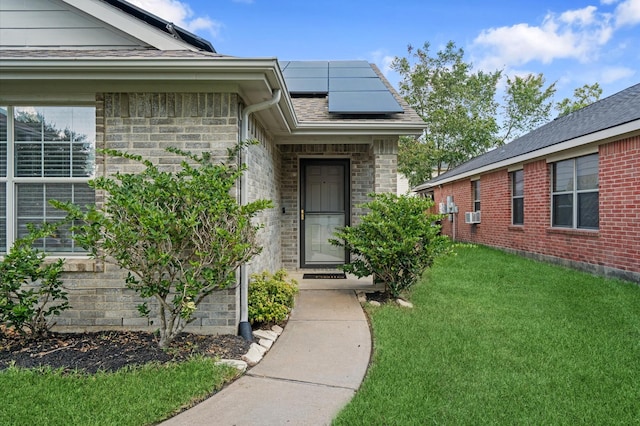 view of exterior entry with a lawn and solar panels