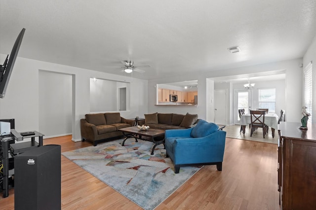 living room featuring light hardwood / wood-style floors and ceiling fan with notable chandelier