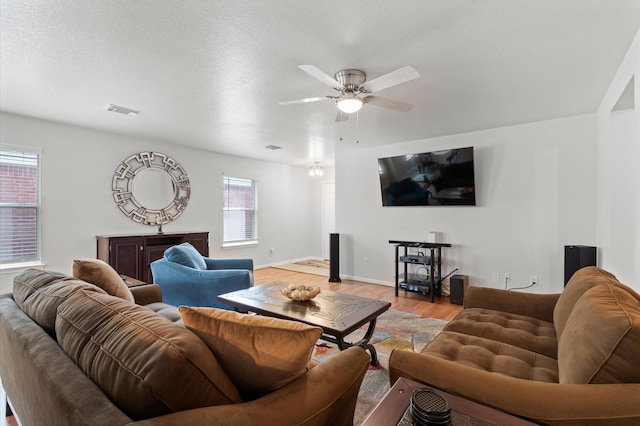 living room featuring light wood-type flooring, ceiling fan, and a wealth of natural light