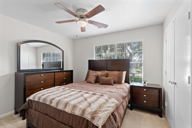 bedroom with a closet, ceiling fan, and light colored carpet