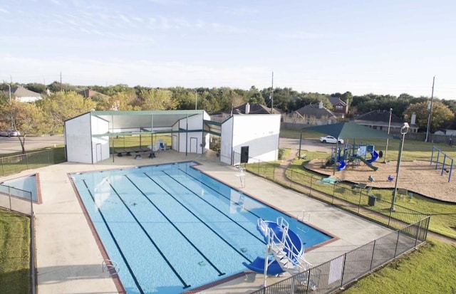 view of swimming pool featuring a patio and a playground