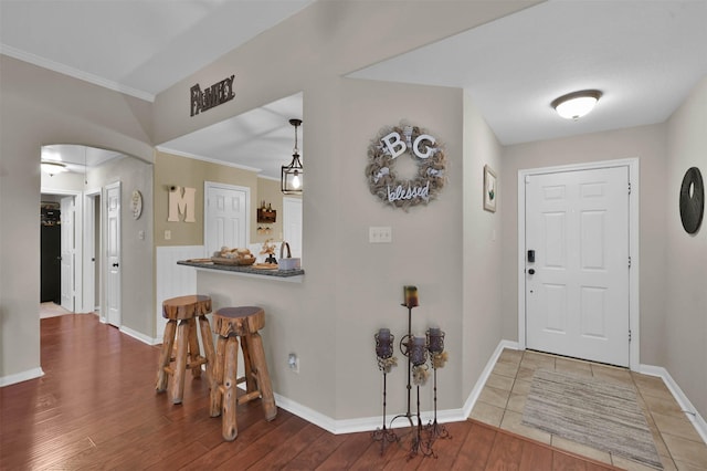 entryway with hardwood / wood-style floors and crown molding