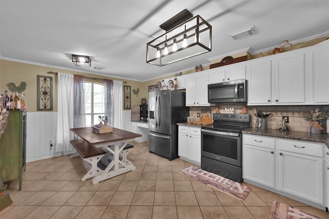 kitchen featuring stainless steel appliances, ornamental molding, light tile patterned floors, and white cabinetry