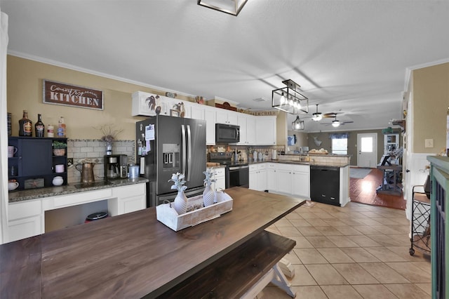 kitchen with white cabinetry, light tile patterned floors, hanging light fixtures, black appliances, and crown molding