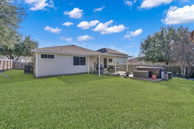 back of property with a patio area, central air condition unit, a lawn, and a hot tub