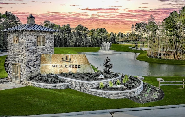 view of home's community featuring a lawn and a water view