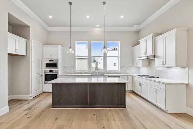 kitchen featuring hanging light fixtures, stainless steel appliances, decorative backsplash, a kitchen island, and white cabinetry