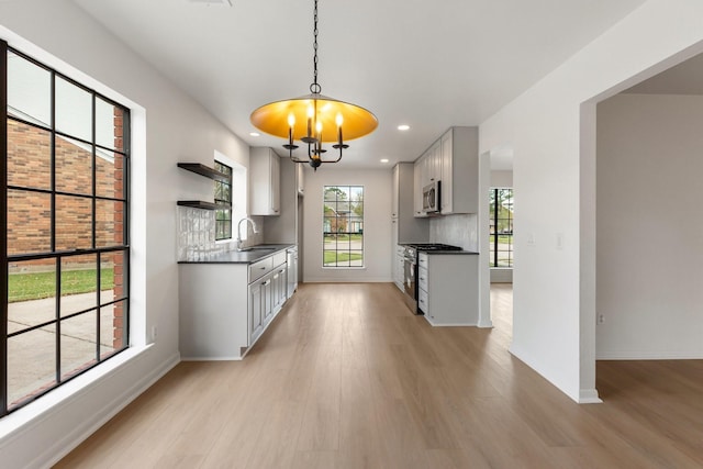 kitchen with sink, backsplash, stainless steel appliances, light hardwood / wood-style floors, and white cabinets