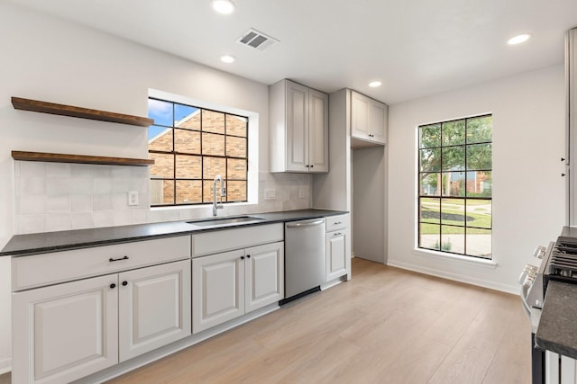 kitchen featuring dishwasher, sink, decorative backsplash, and light hardwood / wood-style flooring