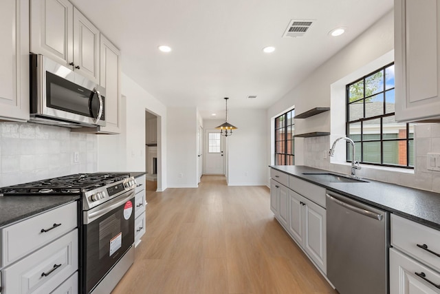 kitchen featuring stainless steel appliances, white cabinetry, sink, and light hardwood / wood-style flooring