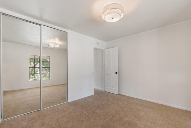 unfurnished bedroom with crown molding, light colored carpet, and a closet