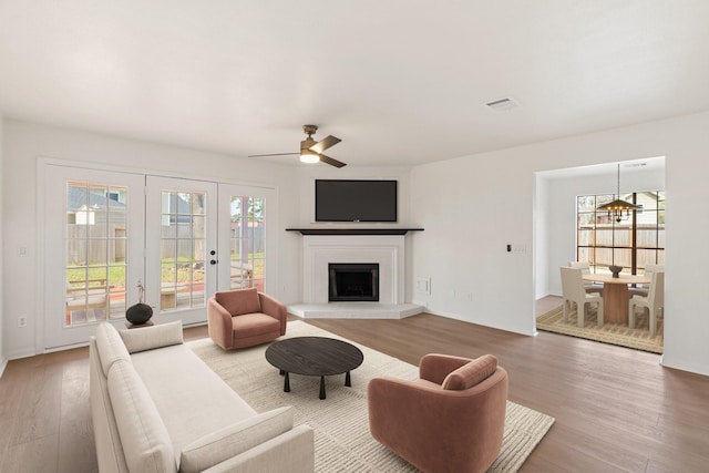 living room featuring ceiling fan with notable chandelier and hardwood / wood-style floors