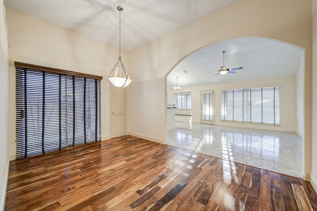 unfurnished dining area featuring ceiling fan with notable chandelier, plenty of natural light, and hardwood / wood-style floors