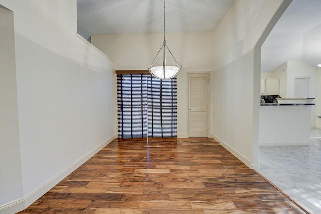 unfurnished dining area featuring hardwood / wood-style floors and vaulted ceiling