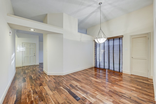 unfurnished dining area with high vaulted ceiling and wood-type flooring