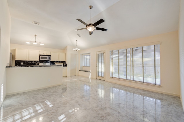 unfurnished living room with lofted ceiling, plenty of natural light, and ceiling fan with notable chandelier