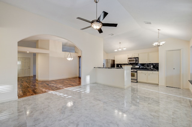 unfurnished living room with ceiling fan with notable chandelier and lofted ceiling