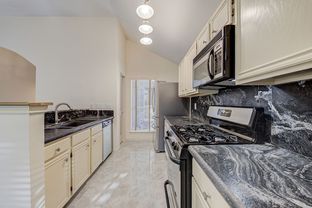 kitchen featuring sink, cream cabinetry, dark stone countertops, decorative backsplash, and appliances with stainless steel finishes