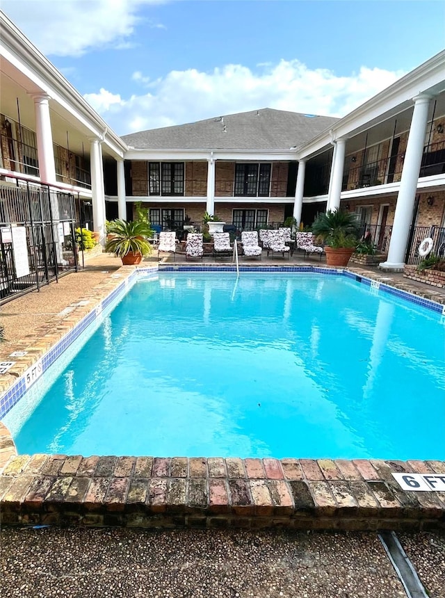 community pool with fence and an outdoor hangout area