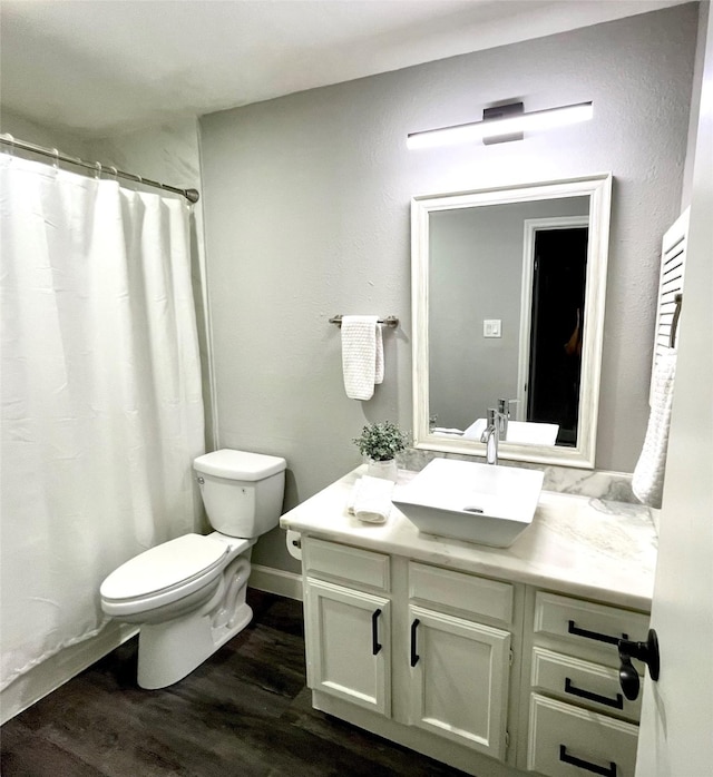 full bath with baseboards, toilet, a shower with shower curtain, wood finished floors, and vanity