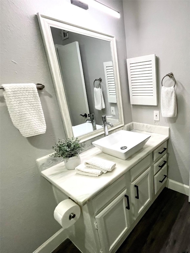 bathroom with vanity, wood finished floors, and baseboards