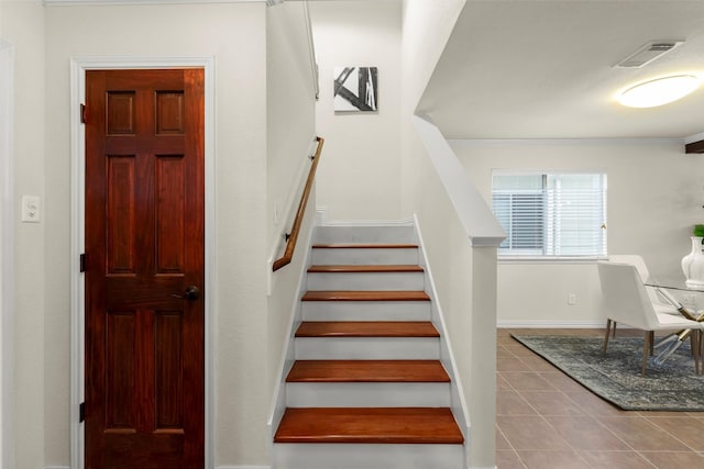 stairs with tile patterned floors and crown molding