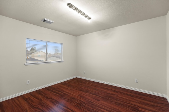 empty room featuring a textured ceiling and dark wood-type flooring