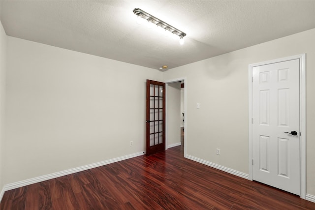 spare room with a textured ceiling and dark hardwood / wood-style floors