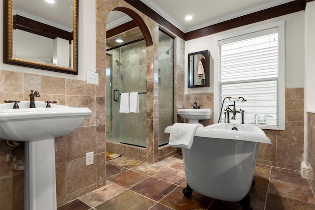 bathroom featuring tile walls, ornamental molding, double sink, and a shower with shower door