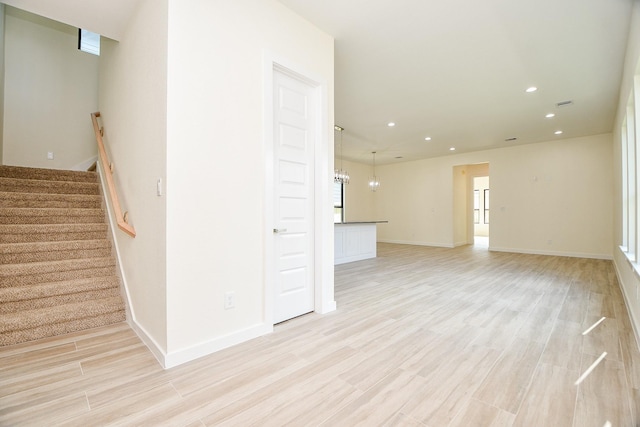 unfurnished living room with light hardwood / wood-style floors and a notable chandelier