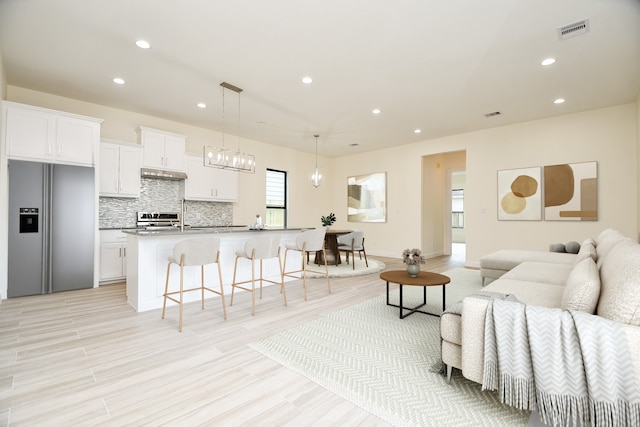 living room featuring sink, a chandelier, and light hardwood / wood-style flooring