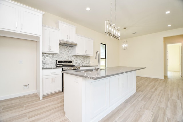 kitchen featuring pendant lighting, an island with sink, white cabinetry, and gas stove