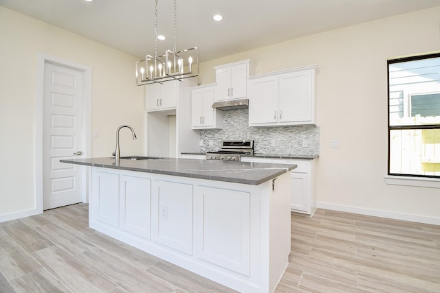 kitchen with sink, an island with sink, white cabinets, and stainless steel range oven