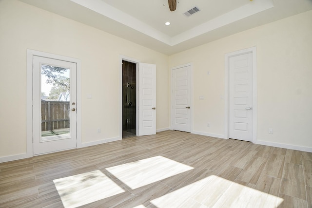 unfurnished bedroom featuring access to outside, a raised ceiling, ceiling fan, and light hardwood / wood-style flooring