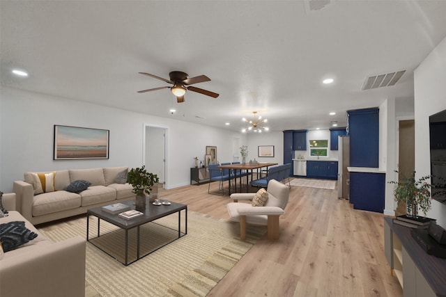 living room featuring ceiling fan with notable chandelier and light hardwood / wood-style floors