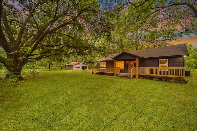 view of front of house with a storage unit, a deck, and a yard