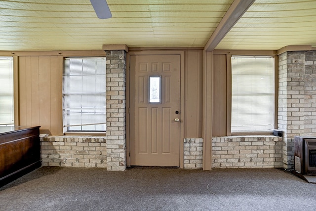 carpeted entrance foyer with brick wall and wooden walls